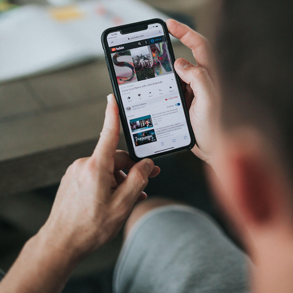 Image of a man's hands holding an older model iPhone.